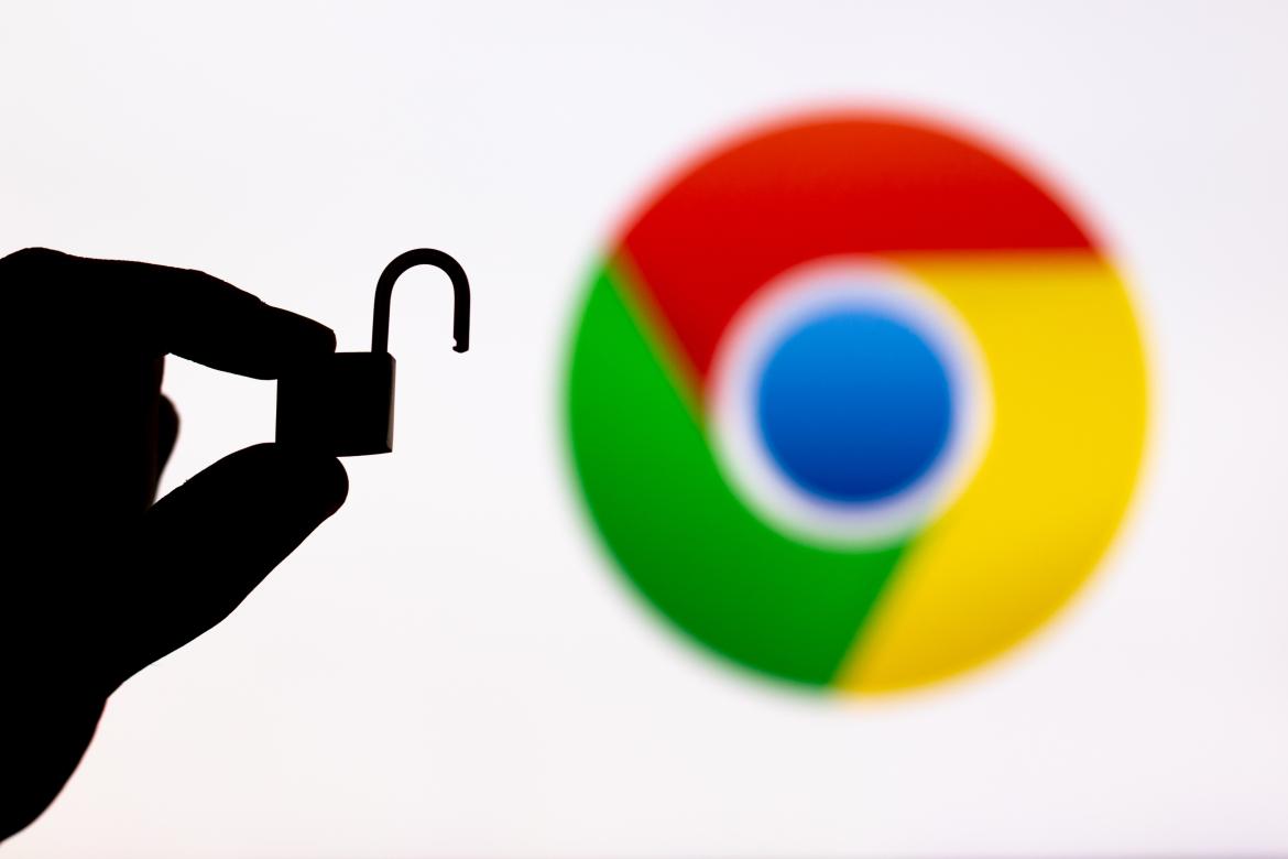 A hand is holding an opened padlock. In the background, there is a blurred Google Chrome logo.